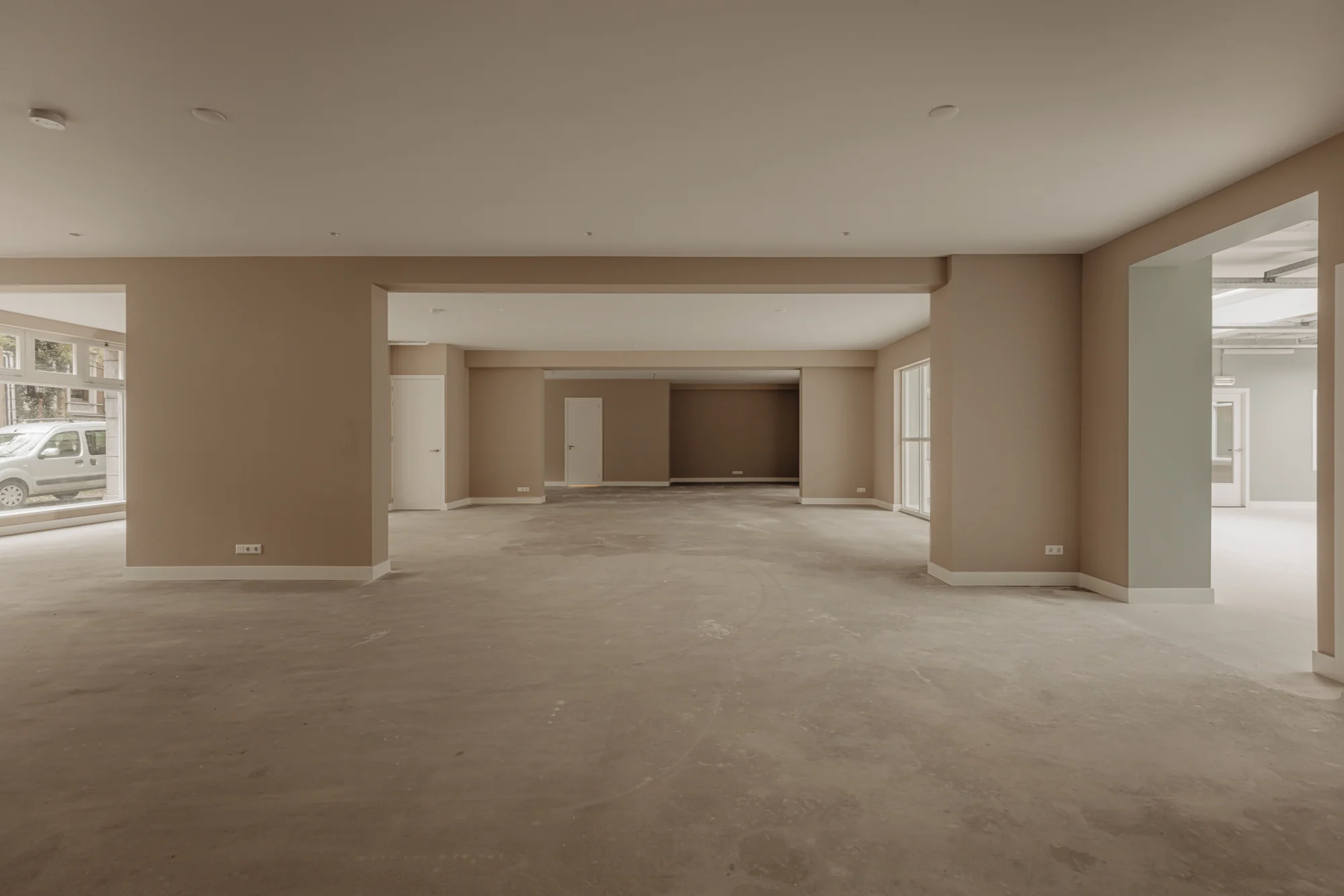 Leegstaand, ruim en licht commercieel pand aan de Henri Polaklaan met grote ramen en betonnen vloer.